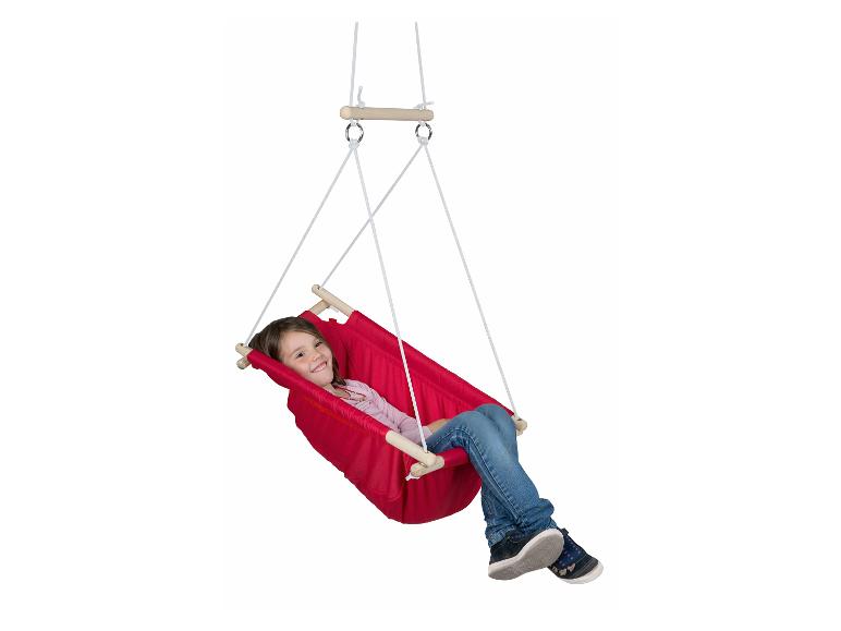 Een lachend meisje schommelt in een rode stoffen schommel