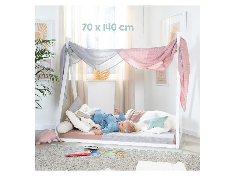 Wit juniorbed met hemel en een kind dat erop ligt, afmeting 70 x 140 cm.