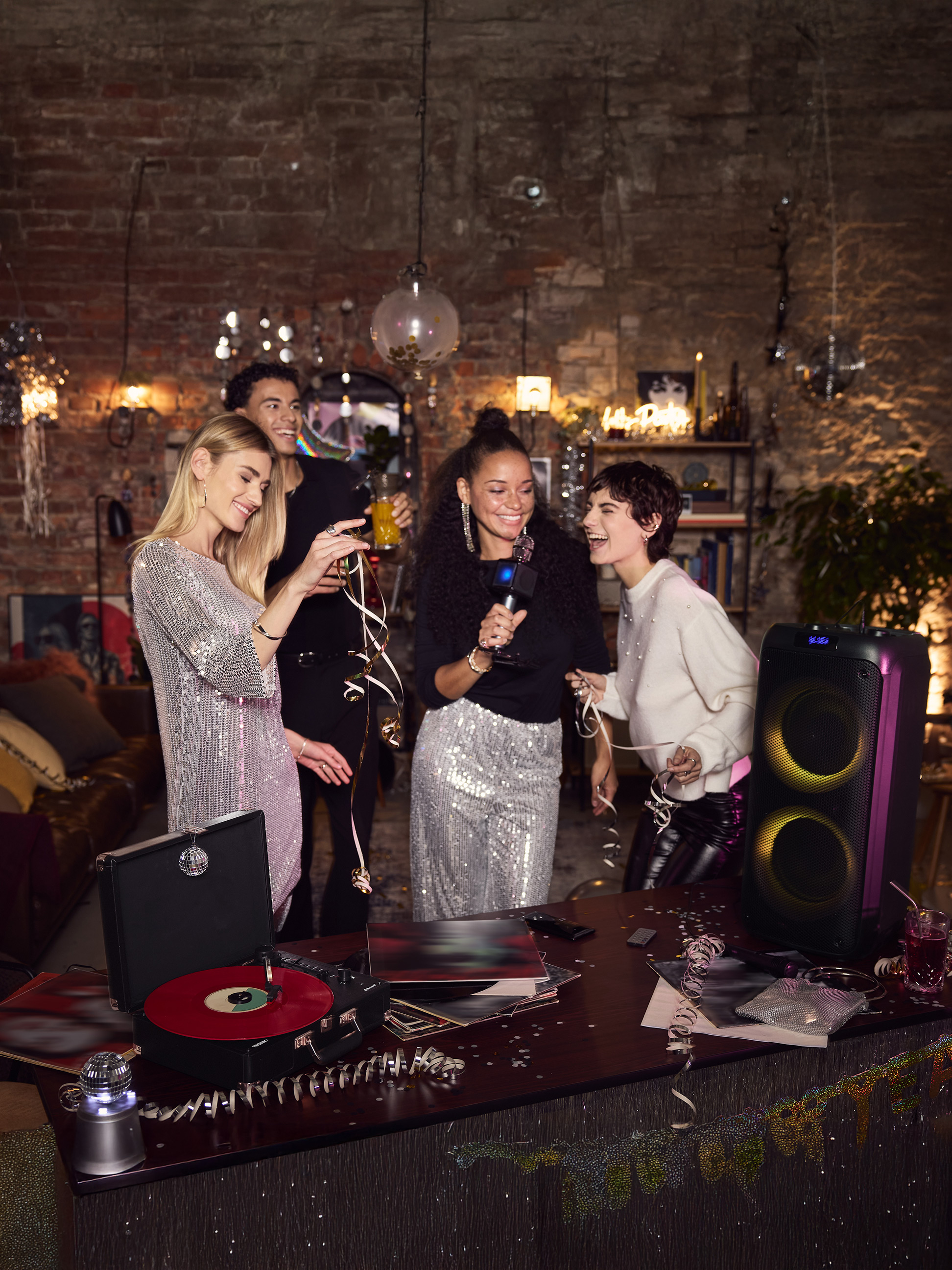 Vrienden zingen karaoke met een luidspreker en platenspeler op een feestje.