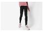 Vrouw in roze trui en zwarte legging met beige sneakers