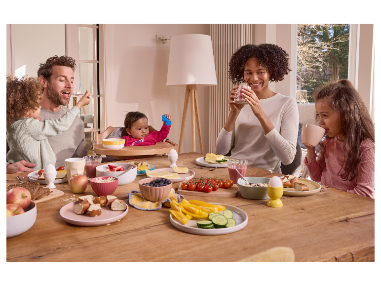 Een gezin geniet samen van een gezond ontbijt aan een robuuste houten tafel.
