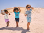 Kinderen in zomerkleding spelen op het strand.
