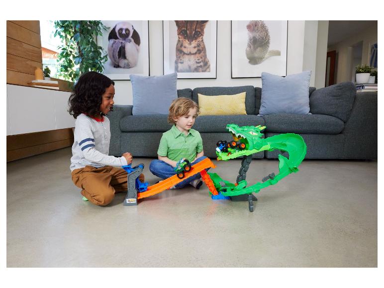 Twee jongens spelen met een monstertruckbaan met een groene draak.