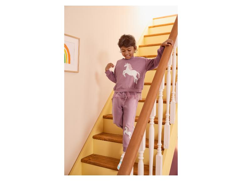 Meisje in paars eenhoorn trainingspak loopt de trap af.