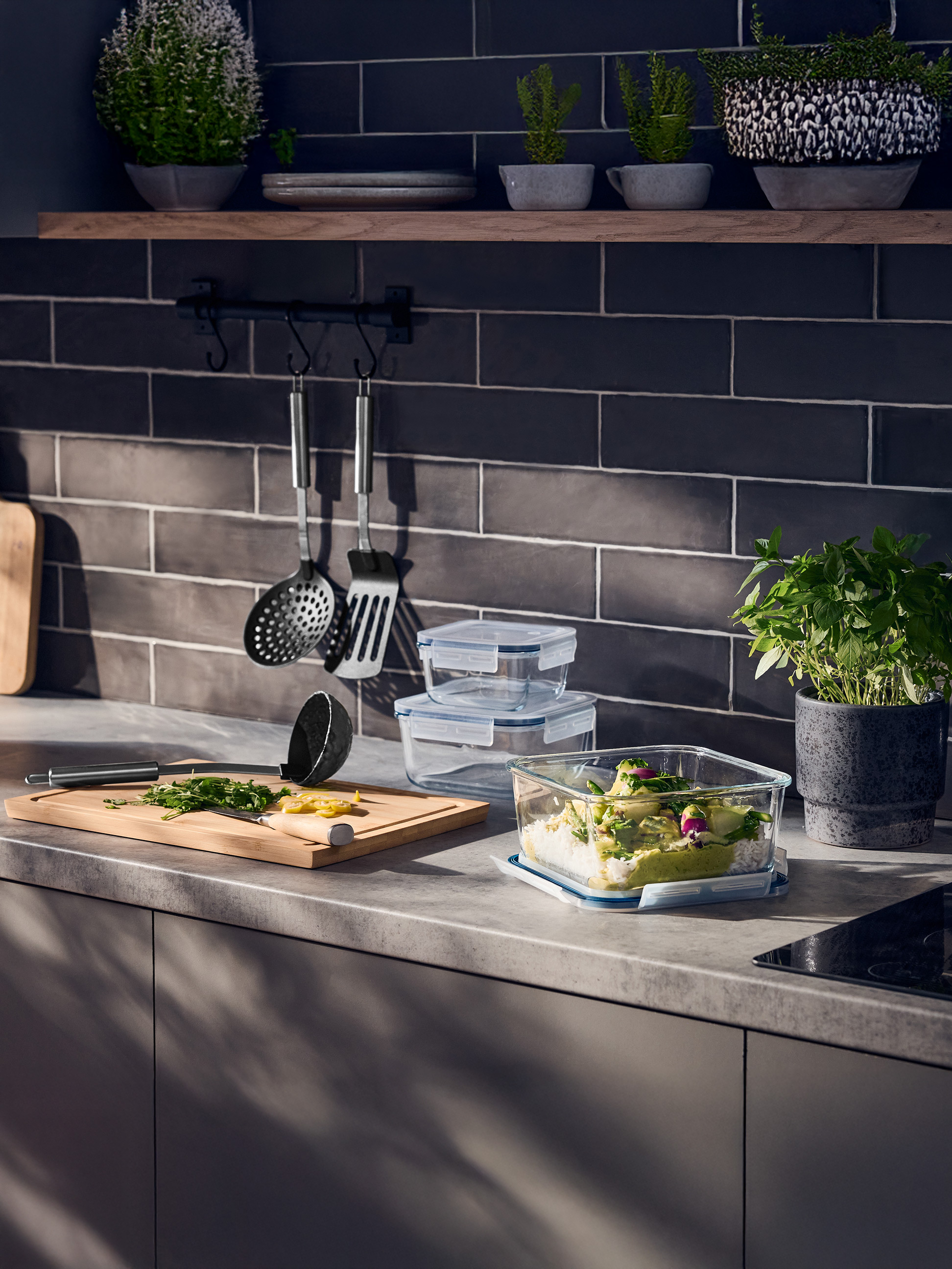 Aanrecht met glazen voedselbewaarbakjes, snijplank en kruiden.