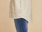 Een licht beige overhemd en blauwe jeans.