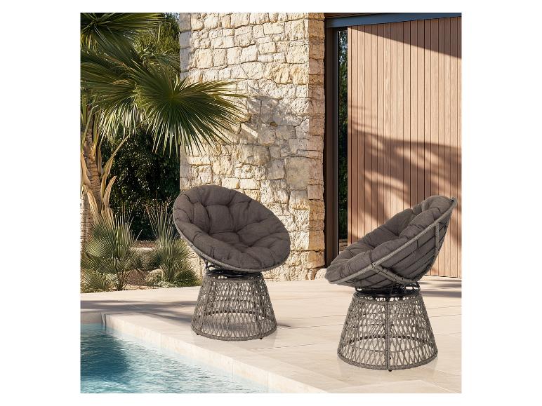 Twee grijze tuinstoelen met kussens bij het zwembad, voor een stenen muur en palmbomen.