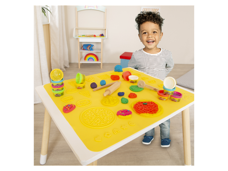 Een kind speelt met Play-Doh klei aan een tafel met een speciale mat.