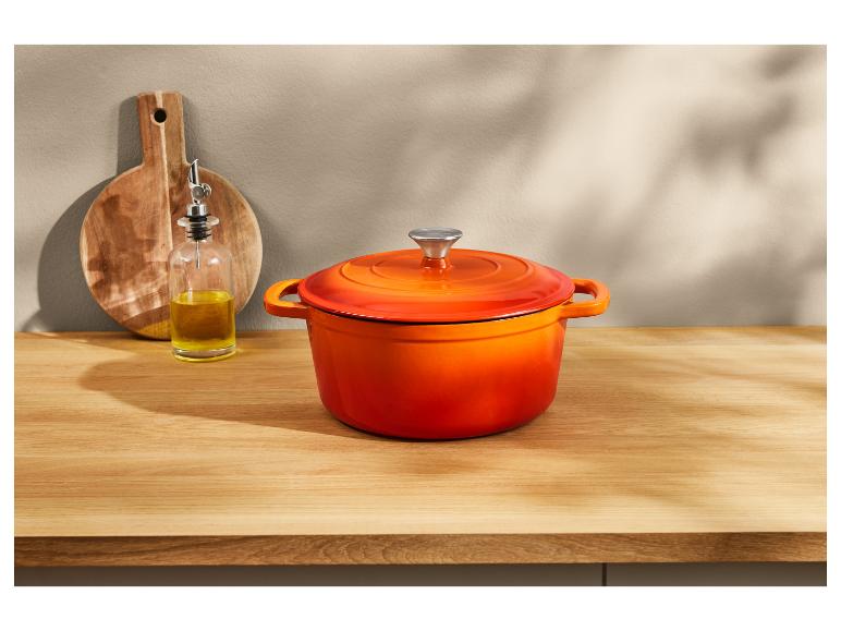 Oranje Le Creuset gietijzeren pan op een houten aanrecht.
