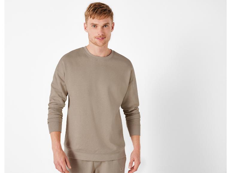 Man in een beige trui en broek.