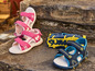 Roze en blauwe sandalen voor kinderen op een stenen oppervlak.