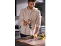 Man in de keuken maakt pesto met een staafmixer.