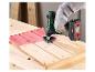 Draadloos multifunctioneel gereedschap schuurt een rood geverfd houten oppervlak.