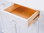 Een open lade van een witte dressoir met houten binnenkant.