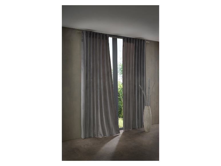 Donkergrijze fluwelen gordijnen hangend in een raam.