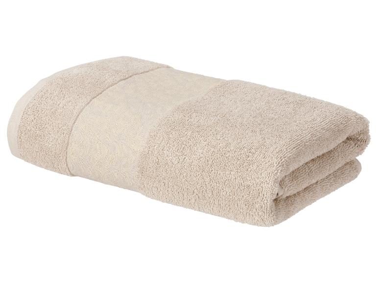 Opgevouwen beige badhanddoek met een decoratieve streep