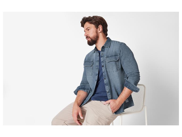 Man draagt een denim overhemd en beige broek.