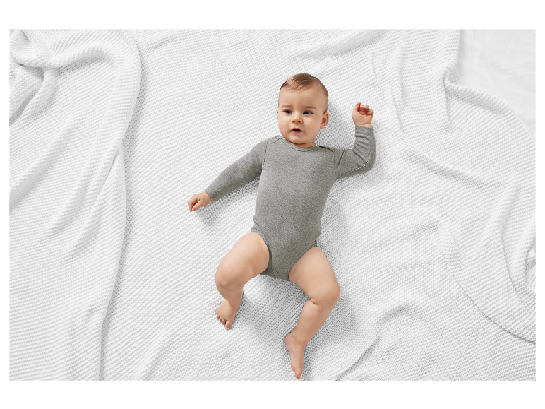 Babybody op een wit gebreid dekentje.