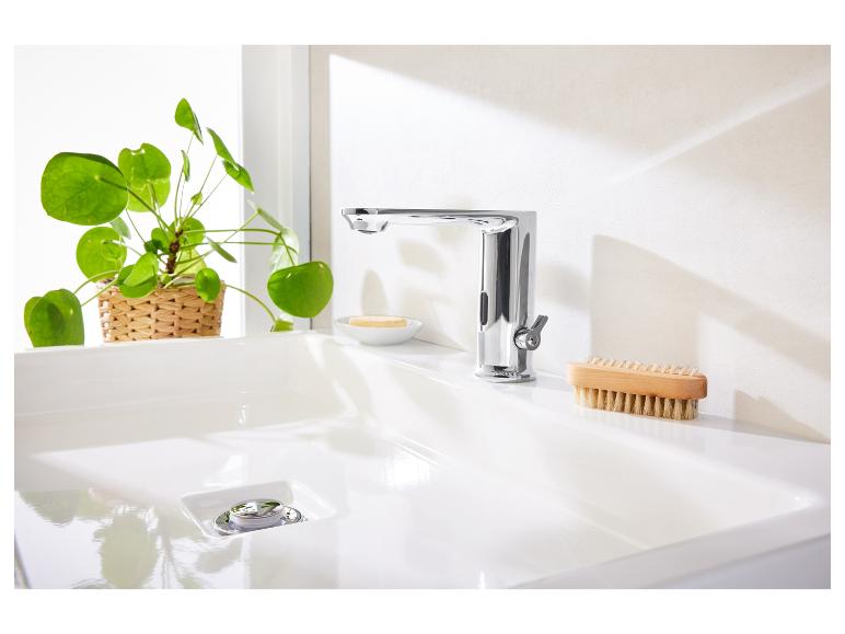 Moderne kraan, wit wasbak en houten borstel.