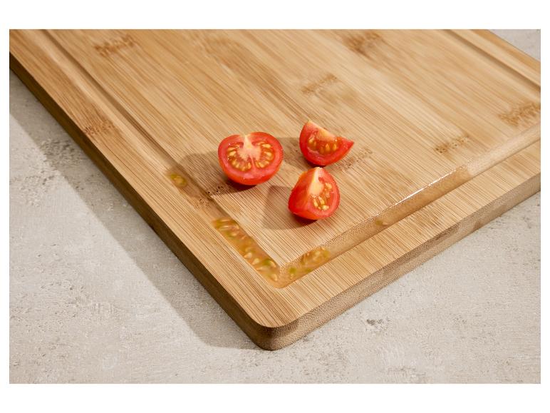 Bamboe snijplank met gesneden cherrytomaten en sap.