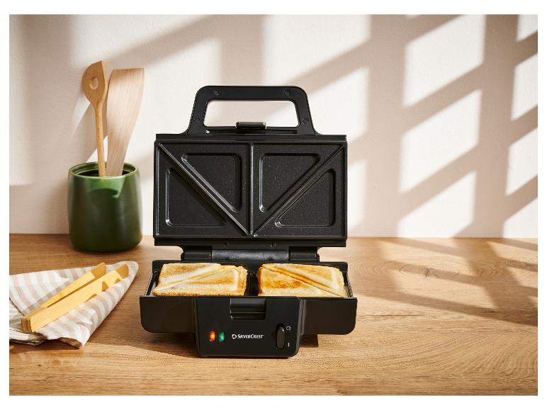 Open SilverCrest tosti-apparaat met twee tosti's op een houten aanrecht.