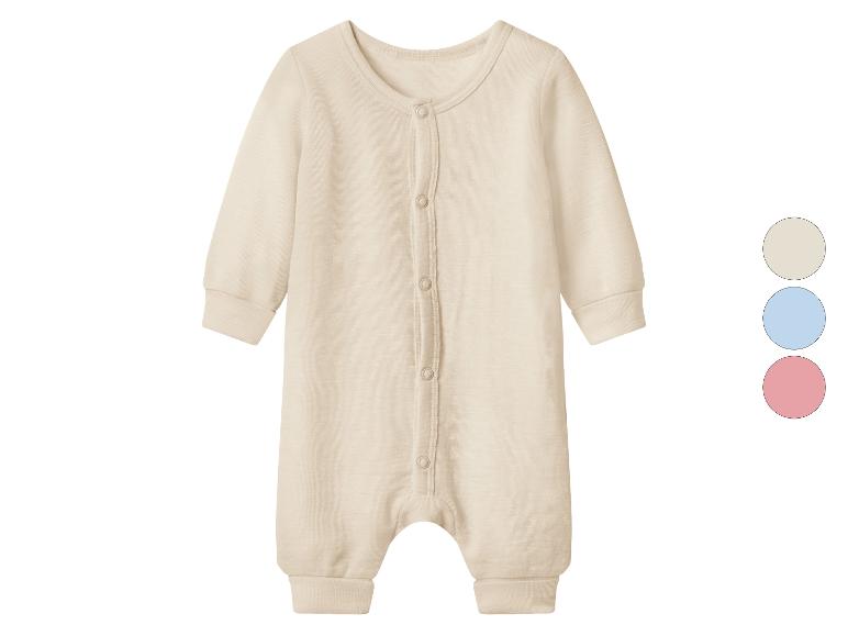 Lichtbeige babyromper met knoopjes en kleurstalen in beige, blauw en roze.