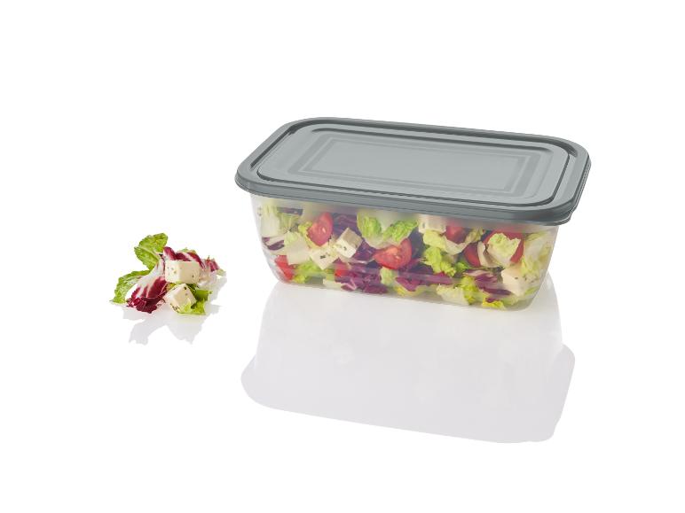 Salade in een transparante bak met grijs deksel.