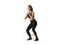 Vrouw in zwarte sportkleding doet squats met een weerstandsband.