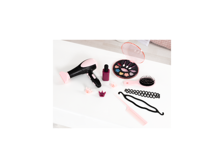 Speelgoedhaardroger, make-uppalet, haarborstel en stylingaccessoires op een wit oppervlak.
