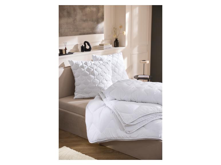 LIVARNO home 4-seizoentendekbed op een bed met kussens.