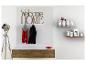 Een houten 'Welcome Home' bord boven een dressoir met laden en een vloerlamp.