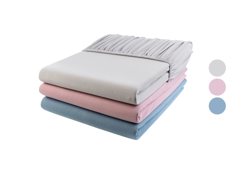 Een stapel bedlakens in grijs, roze en blauw.