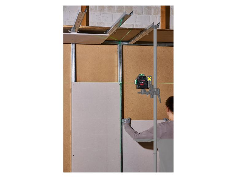 Een laserwaterpas op een paal helpt een werknemer bij het installeren van gipsplaten.