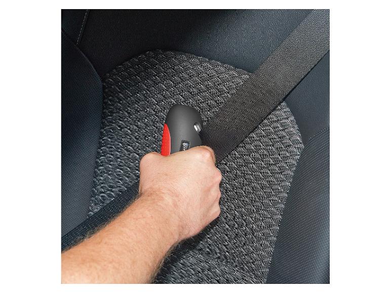 Man houdt zwarte gordelsnijder met rode knop vast in auto.