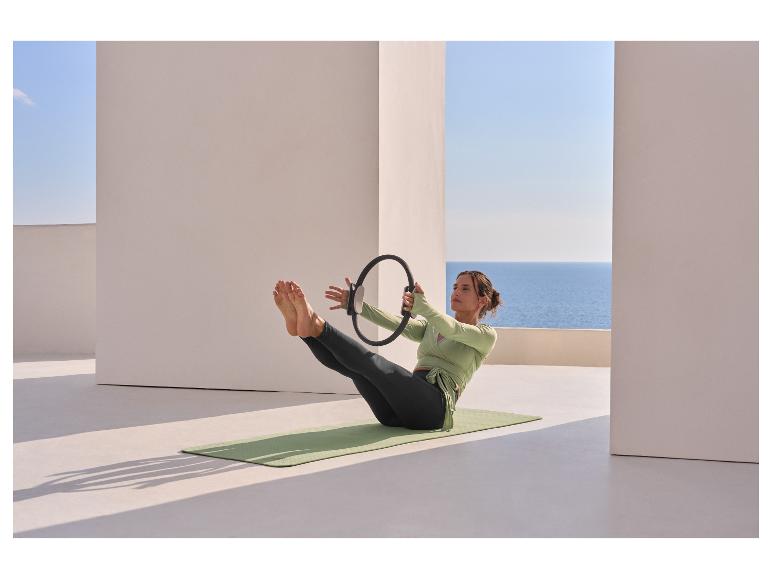 Vrouw in CRIVIT functionele top doet pilates met een ring op een mat.