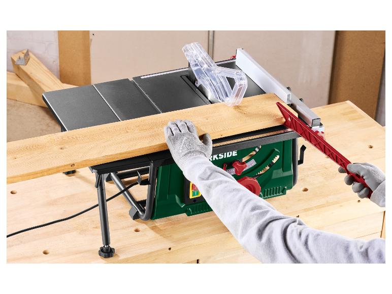 Tafelzaag snijdt een houten plank, met gehandschoende handen en een duwstok
