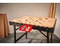 Een werkbank met een geperforeerd houten blad, met twee rode bakken met schroeven en houten deuvels.