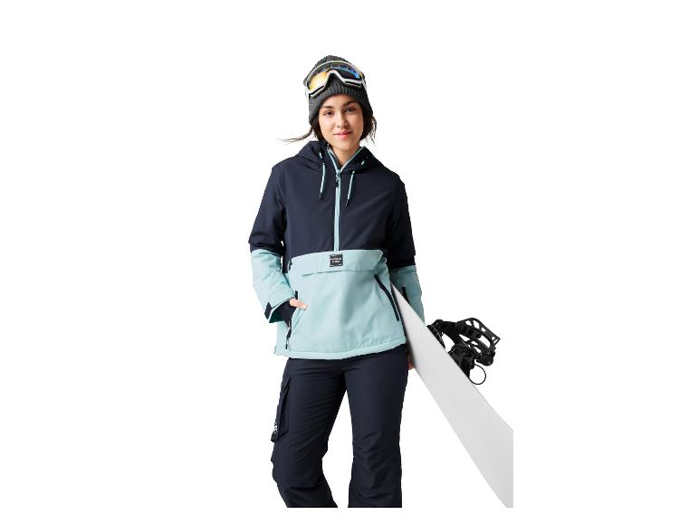 Vrouw met skibril en snowboard, draagt een winterjas en broek.