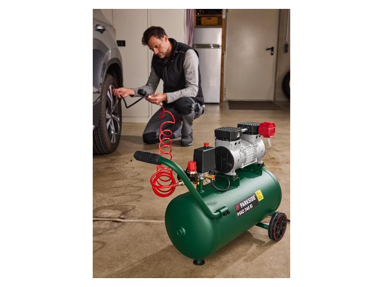 Een man gebruikt een Parkside luchtcompressor om een autoband op te pompen in een garage.