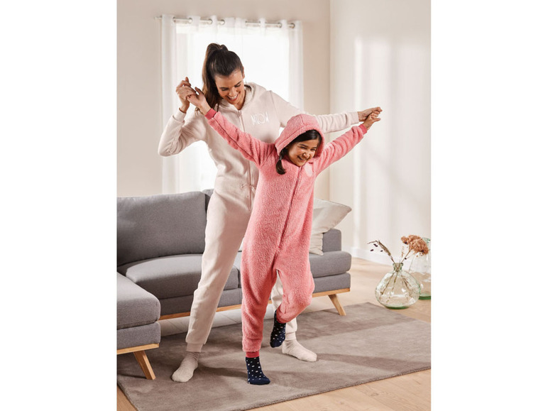 Een moeder en dochter dragen pyjama's in een woonkamer.