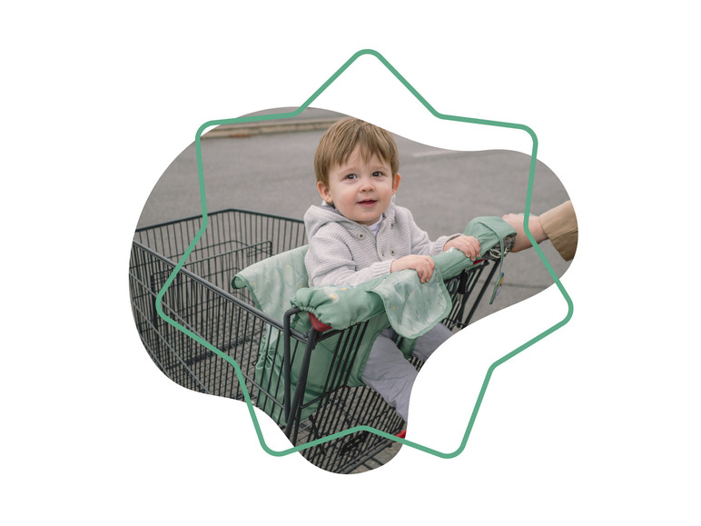 Een kind zit in een winkelwagen met een groene zitting.