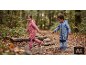 Kinderen in regenpakken en regenlaarzen spelen in een plas in het bos.