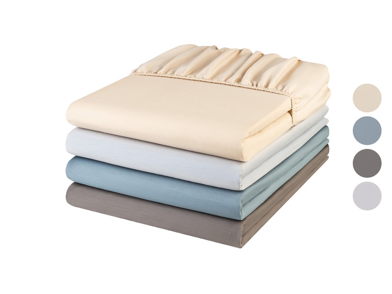 Een stapel bedlakens in crème, lichtblauw, donkerblauw en grijs.