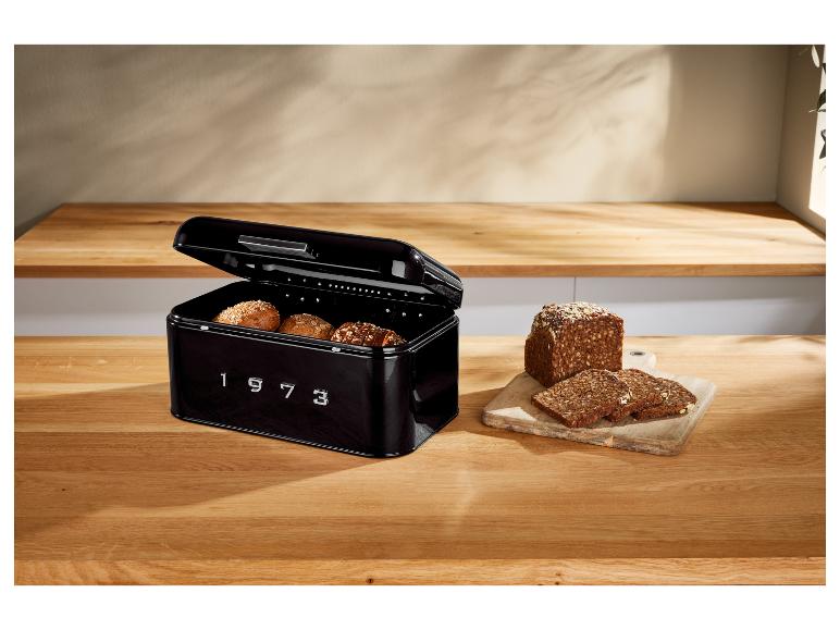 Zwarte retro broodtrommel met brood op een houten tafel.