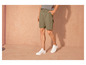 Man draagt groene shorts en witte sneakers.