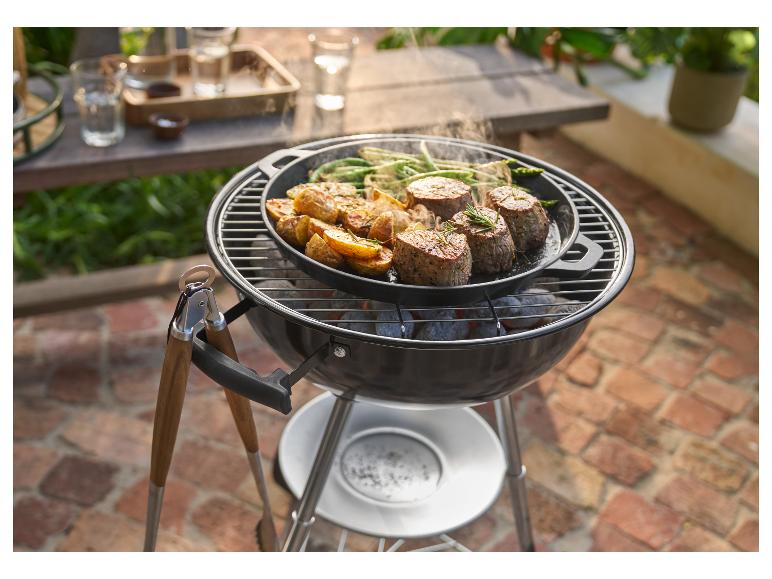 Barbecue met pan gegrild vlees, aardappelen en sperziebonen, met tang ernaast.