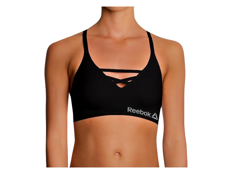 Zwarte Reebok sportbeha met gekruiste bandjes op een vrouwelijk bovenlichaam.