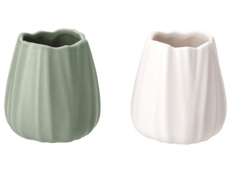 Twee keramische vazen, één saliegroen en één gebroken wit, met een geribbeld patroon.