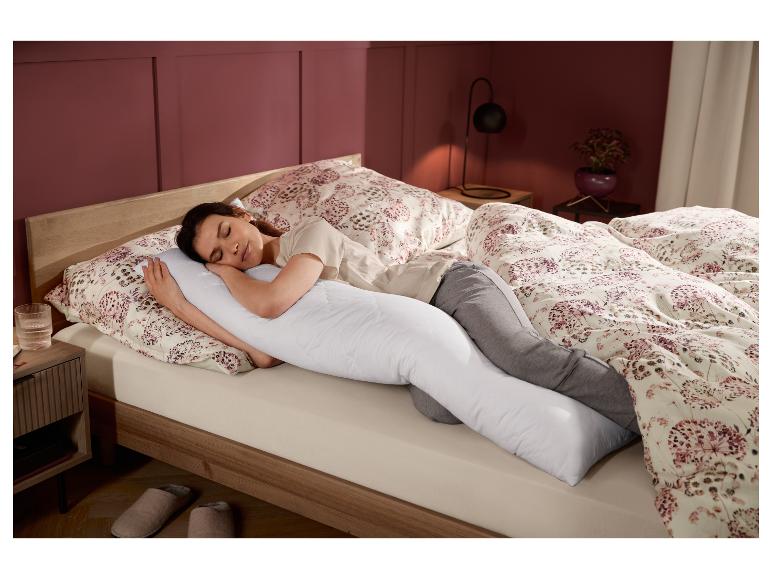 Een vrouw slaapt in bed met een lang kussen.