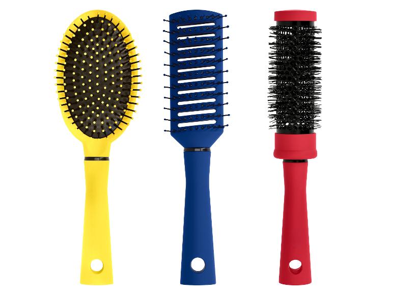 Drie kleurrijke haarborstels: een gele ovale, een blauwe ventilerende en een rode ronde borstel.
